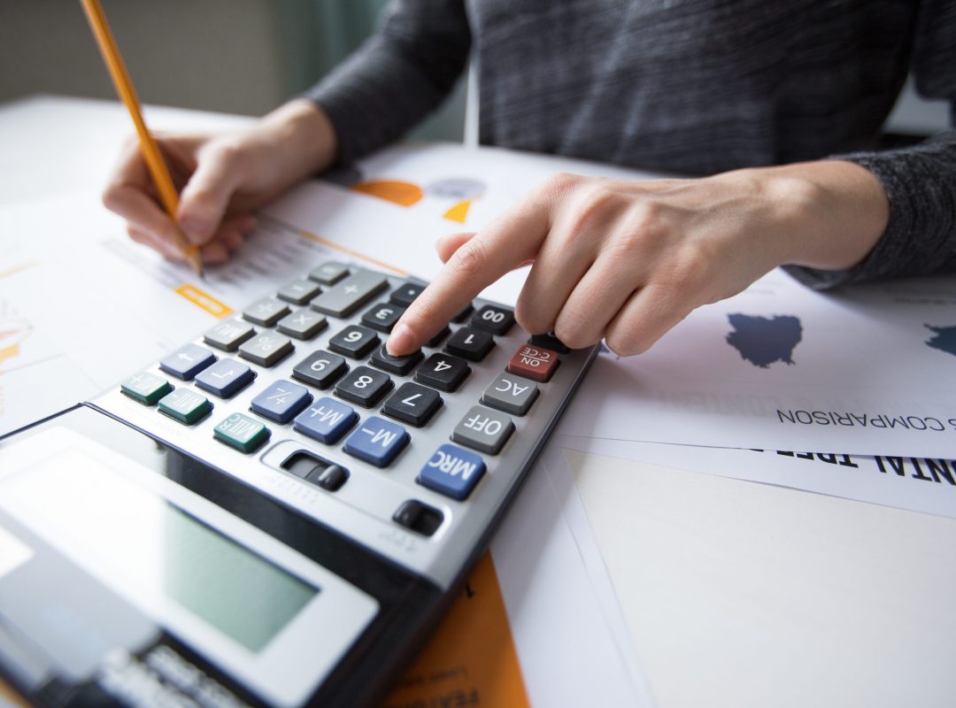 Close-up of female hand counting with calculator Close-up of female hand counting with calculator, papers all around on table. Businesswoman working with documents